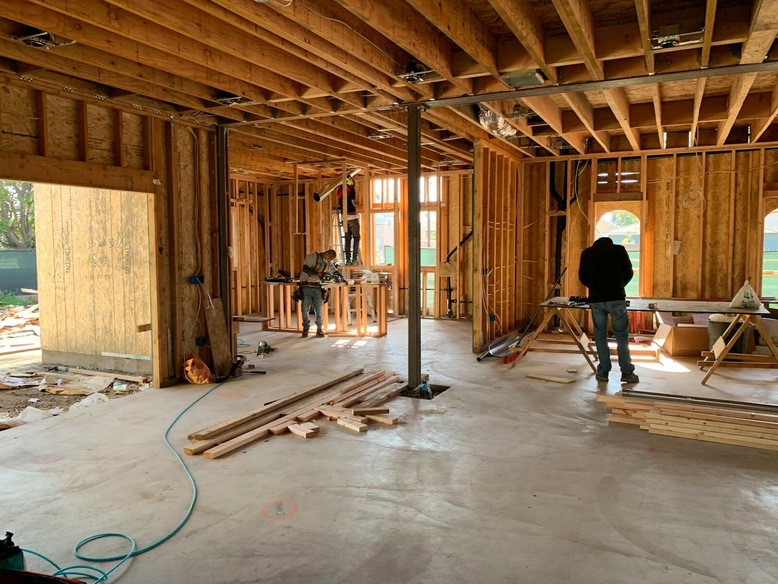 Workers constructing a house framework, showcasing interior carpentry and building process.